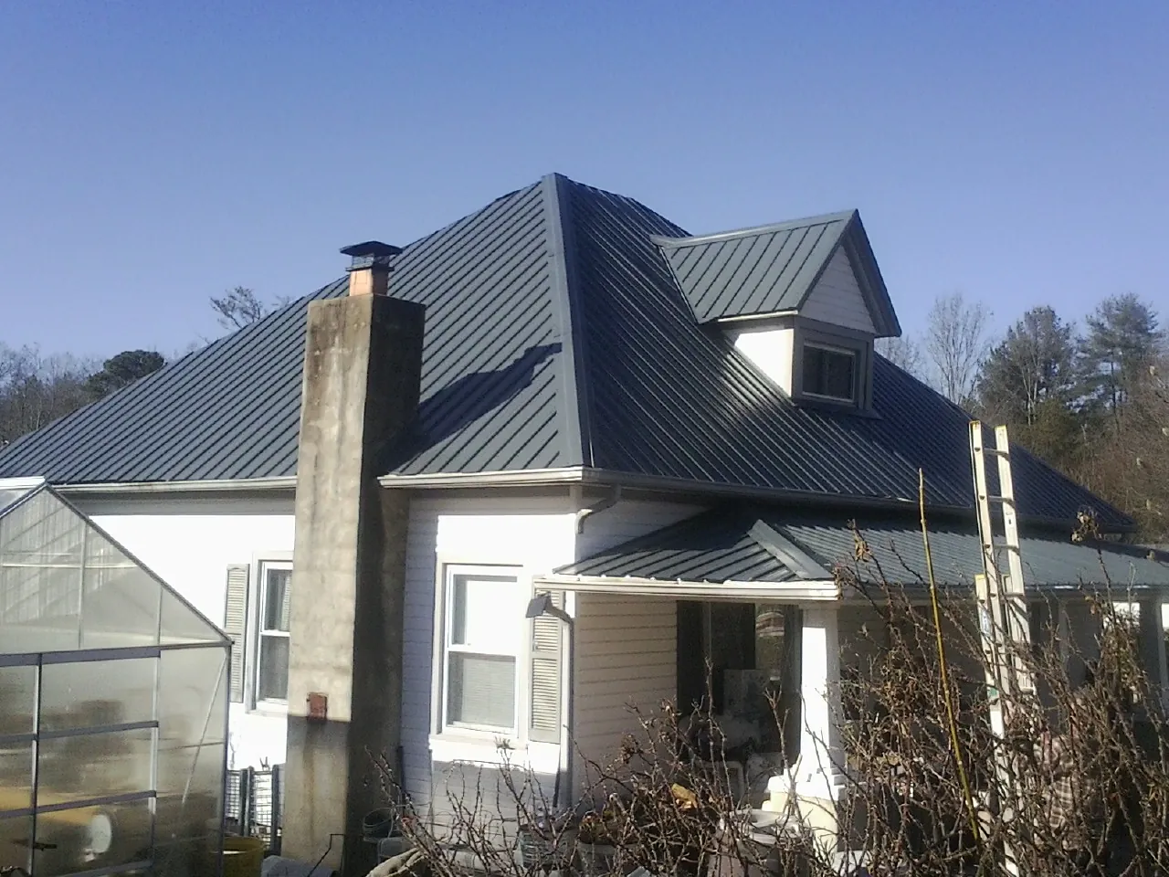 Dark blue standing seam metal roof on a white farmhouse with dormer — Slate & Tile Roof Repair by Roofing Brothers in Orviston