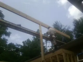 Carpenter setting a ridge beam over a new addition frame — Ice Dam Removal by Roofing Brothers in Orviston
