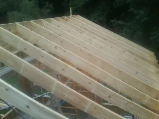 New roof rafters set over an addition before sheathing in Orviston