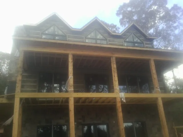 Dormers and porch framing on a large log home under construction — Roof Coating work by our crew in Orviston