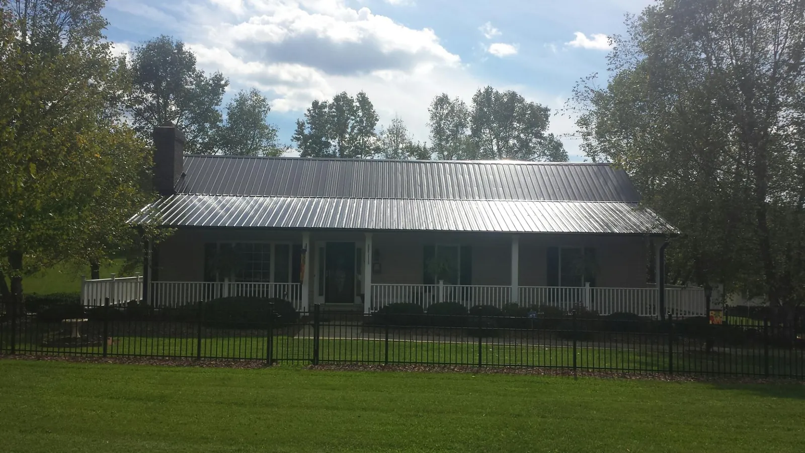 Gray metal roof on a brick ranch with a full width front porch — Gutter Guard Installation work by our crew in Orviston