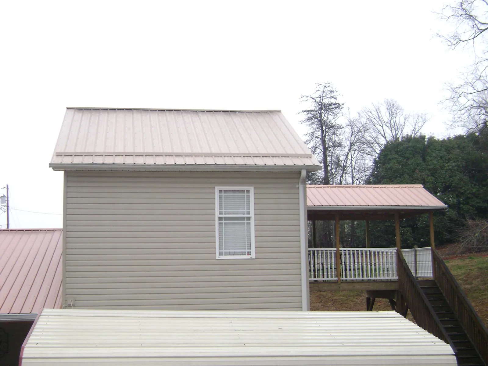 Tan metal roofs on a two story addition and attached porch, from a Roof Replacement job in Orviston