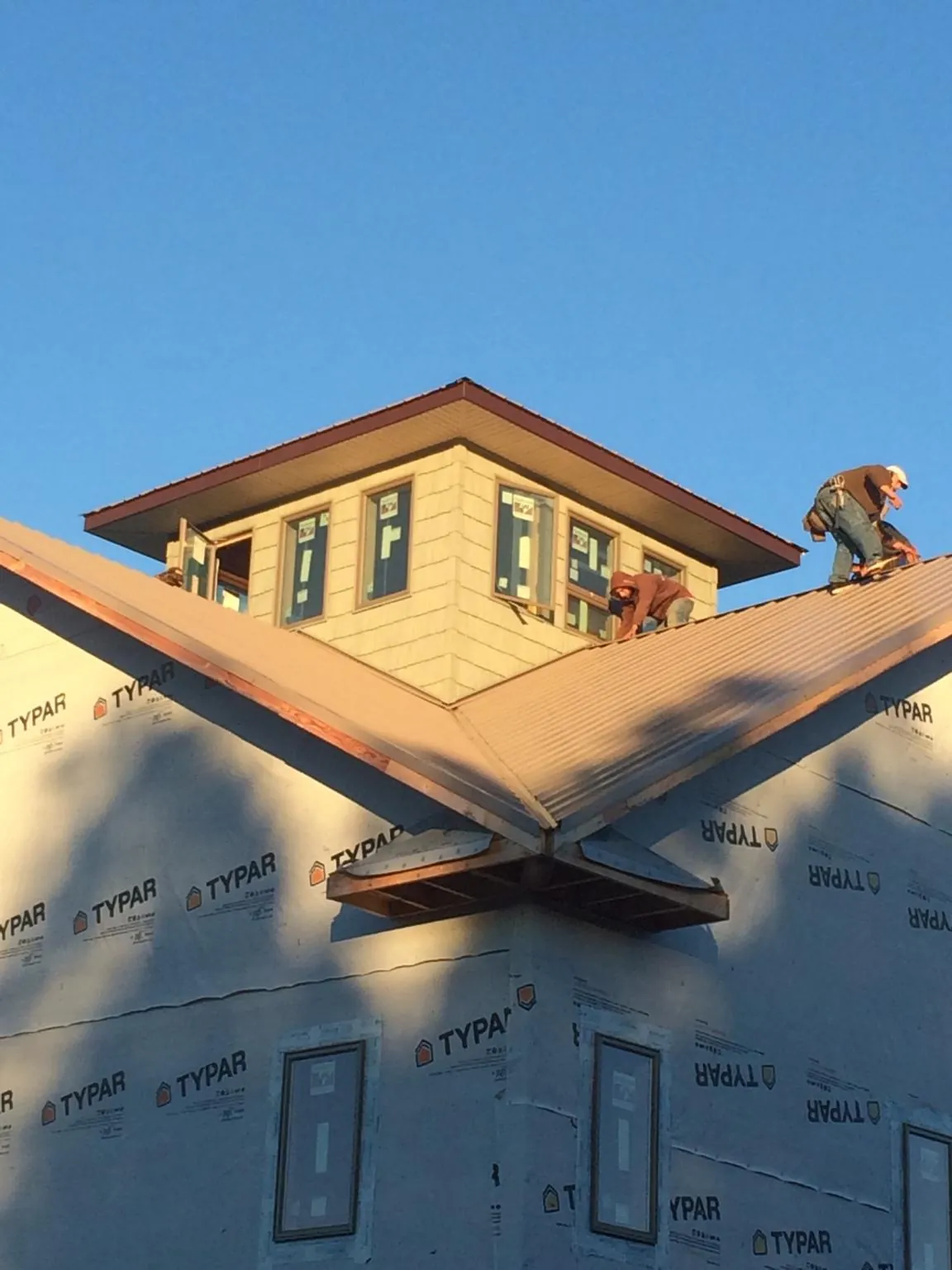 Roofers working around a rooftop cupola on a new metal roof at sunset — Roof Waterproofing in Orviston by Roofing Brothers